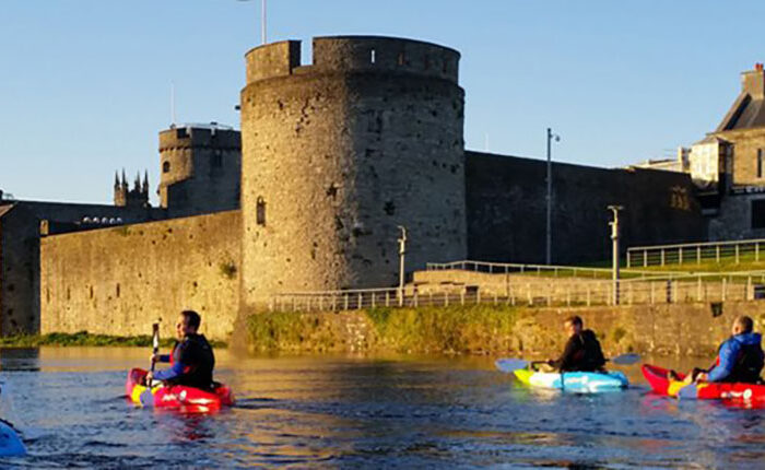 People kayaking on the River Shannon with King Johns Castle in the background.