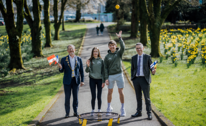 two young people in a city park with a mayor and minister holding small european flags