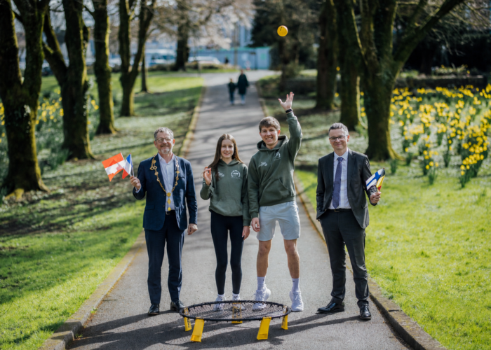 two young people in a city park with a mayor and minister holding small european flags